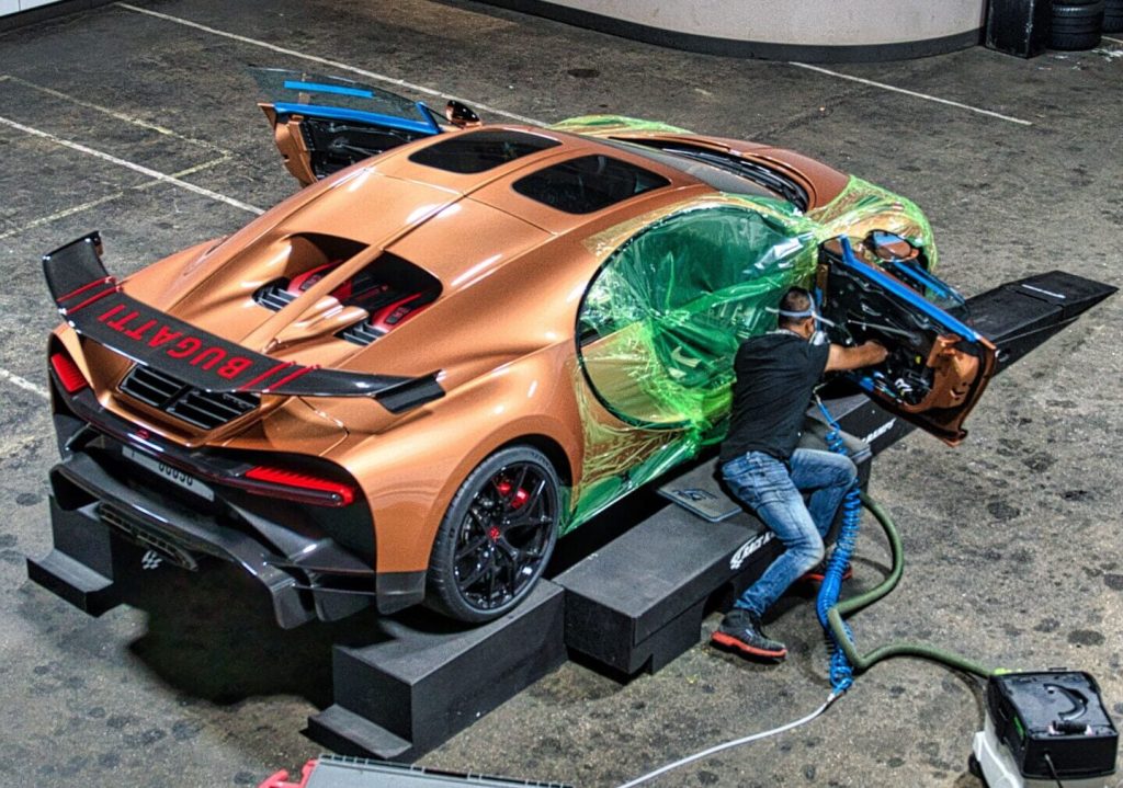 Working on the door of a Bugatti partly wrapped in film