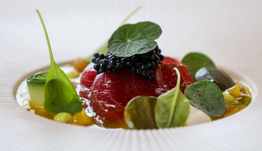 A red dish under dark pearls and round green leaves