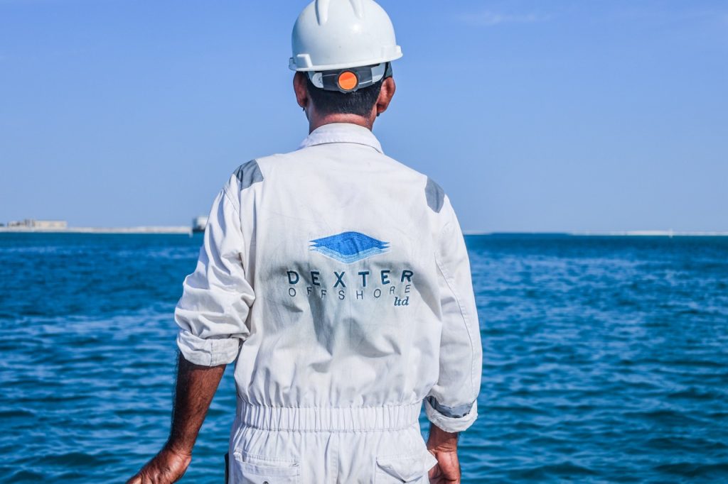 A worker in Dexter Offshore overalls, looking out to sea