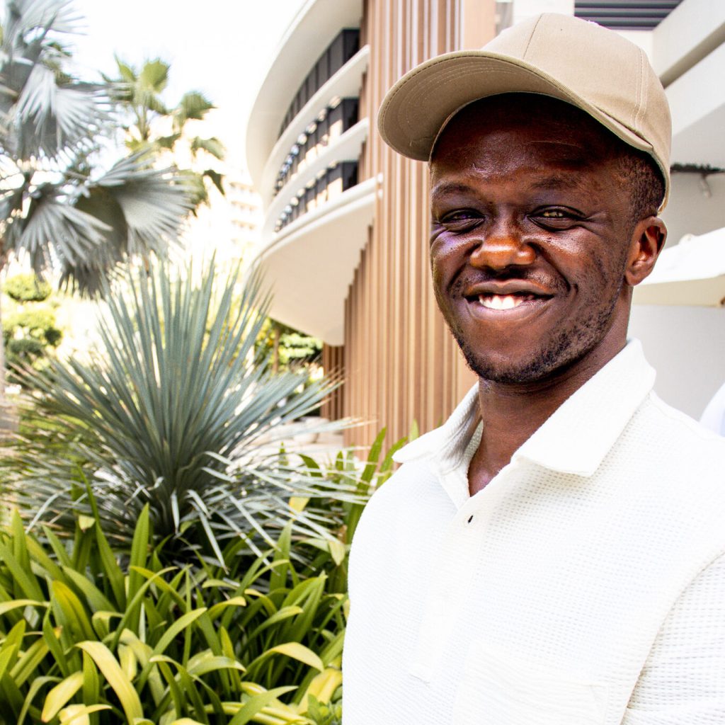 A big smile in a beige cap and white polo
